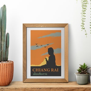 K&ouml;nnte beinhalten: Ein gerahmter Druck mit einem orangefarbenen Sonnenuntergangs-Hintergrund und einer Silhouette einer Person, die den Horizont betrachtet. Der Druck enth&auml;lt den Text "CHIANG RAI" und "เมืองเชียงราย" in Thai.
