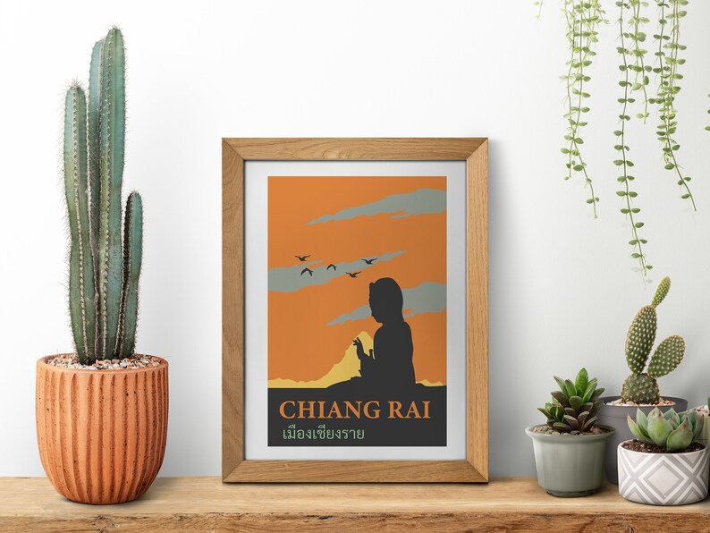 K&ouml;nnte beinhalten: Ein gerahmter Druck mit einem orangefarbenen Sonnenuntergangs-Hintergrund und einer Silhouette einer Person, die den Horizont betrachtet. Der Druck enth&auml;lt den Text "CHIANG RAI" und "เมืองเชียงราย" in Thai.