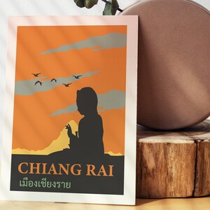 K&ouml;nnte beinhalten: Ein Vintage-Reiseposter mit orangefarbenem Hintergrund und einer Silhouette einer Person, die auf einem Berg sitzt. Das Poster zeigt den Text "CHIANG RAI" in Schwarz und "เชียงราย" in Gr&uuml;n.