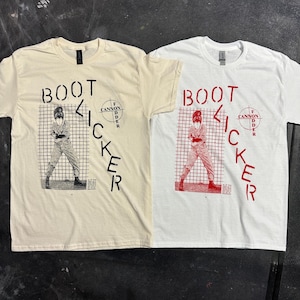 May include: Two t-shirts with the same design. The design features a person in a grid with the words "BOOT KICKER" and "F CANNON FODDER" in red. One shirt is white and the other is beige.