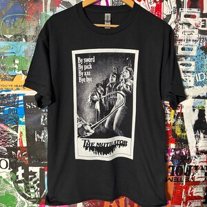 Könnte beinhalten: Schwarzes T-Shirt mit einem weißen Aufdruck eines Filmplakats für "The Mutilator". Das Plakat enthält den Slogan "By sword, By pick, By axe, Bye bye".