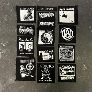 Puede incluir: Una colección de parches de punk rock en blanco y negro. Cada parche presenta diseños y textos únicos, incluidos nombres de bandas y lemas. Los parches son cuadrados o rectangulares y varían en tamaño.