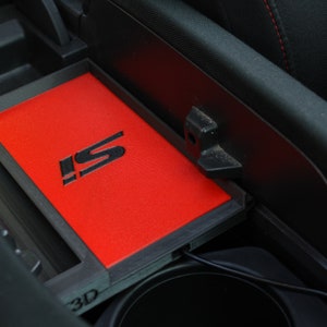 May include: A red car interior with a black center console. The console has a black tray with a red liner and a black "IS" logo. The tray is labeled "3D" in the lower left corner.
