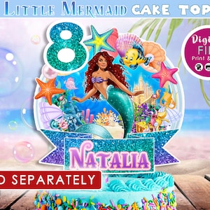 May include: A cake topper featuring a mermaid with red hair and a teal tail, surrounded by sea creatures and the number 8. The name "Natalia" is displayed on a banner. The text "The Little Mermaid Cake Topper" is at the top.