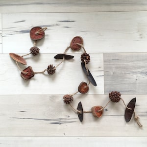 May include: A rustic garland made of dried fruit slices, pine cones, and wood pieces. The garland is strung together with twine and is perfect for adding a touch of natural beauty to your home decor.