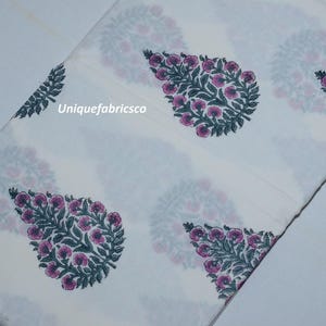 May include: A white fabric featuring a repeating pattern of dark green leaves and pink floral motifs. The text "Uniquefabricsco" is printed in white on the fabric. The material is folded, displaying the botanical print across the surface.