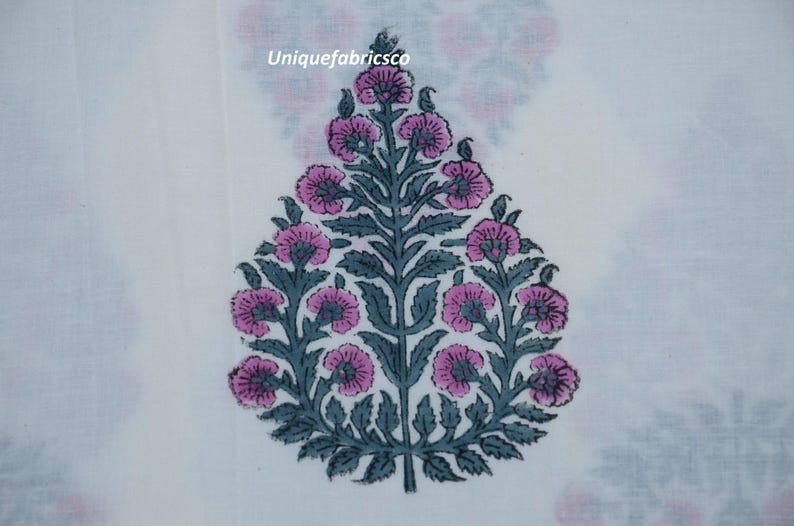 May include: A white fabric featuring a repeating floral motif in shades of pink and dark grey. The central design is a teardrop-shaped plant with pink blossoms and dark grey leaves. The text "Uniquefabricsco" is printed in small white letters.