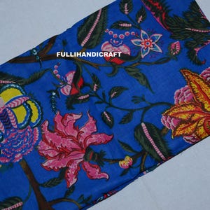 Könnte beinhalten: Ein blauer Stoff mit einem lebendigen Blumenmuster aus großen gelben, rosa und grünen Blüten und Blättern. Der Text FULLIHANDICRAFT ist in Weiß in der Mitte des Stoffes aufgedruckt, der ein sich wiederholendes botanisches Design zeigt.