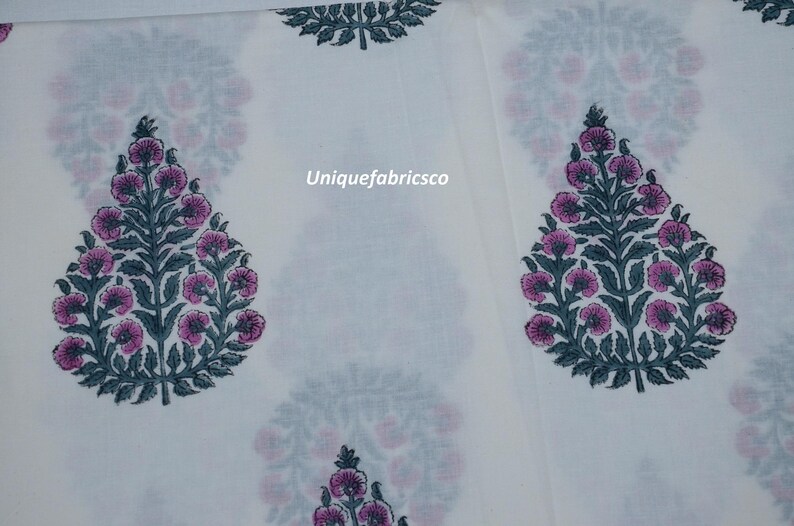 May include: A white fabric featuring a repeating pattern of dark green leafy trees with pink circular flowers. The text Uniquefabricsco is printed in the center of the fabric. The design is arranged in a grid-like layout across the material.