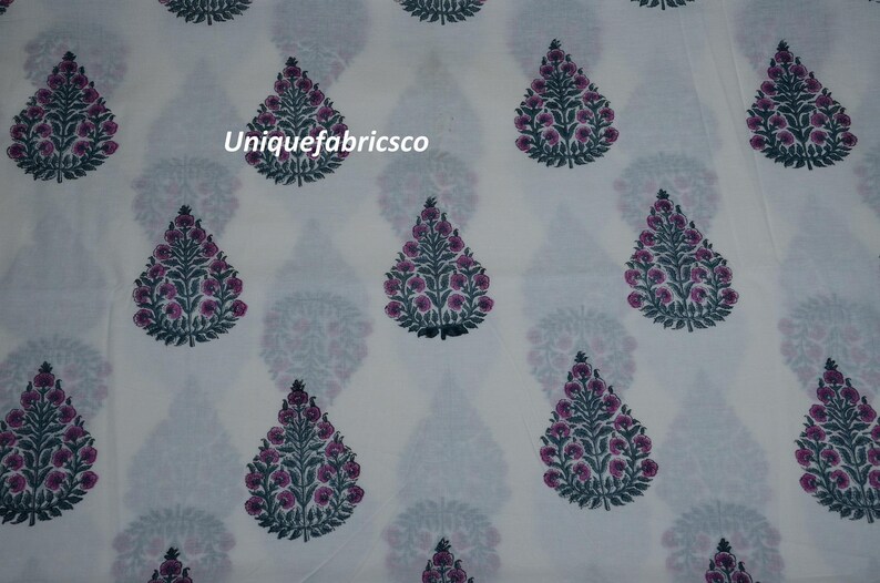 May include: A white fabric featuring a repeating pattern of teardrop-shaped floral motifs in dark green and magenta. Each motif depicts a stylized tree with small circular blossoms. The text "Uniquefabricsco" is printed in white on the fabric.