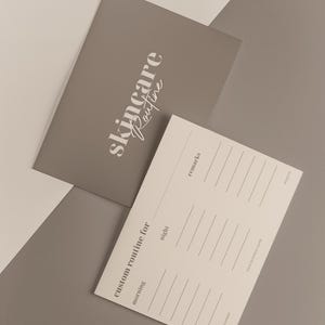 May include: Two gray skincare routine cards. One card has the words "skincare Routine" in white script. The other card has lines for writing and the words "custom routine for" and "morning" and "night".