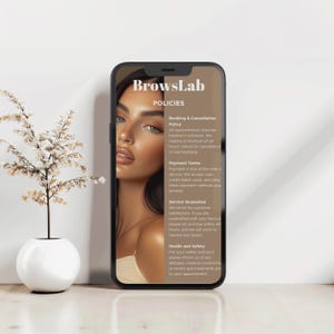 May include: A smartphone displays the "BrowsLab" policies, including booking, payment, service guarantee, and health and safety information. The screen shows a portrait of a woman with expertly styled eyebrows. A small white vase with a decorative plant is in the background.