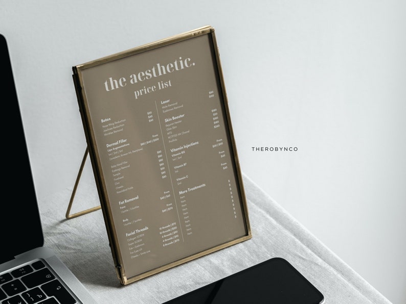 May include: A framed price list titled "the aesthetic. price list" with a gold frame. The list includes services like Botox, Dermal Filler, and Vitamin Injections. A laptop and a smartphone are in the foreground.