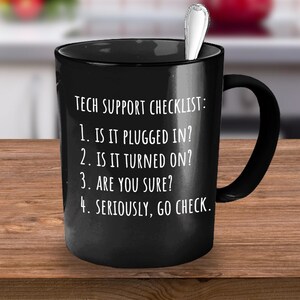 May include: Black coffee mug with white text that reads "TECH SUPPORT CHECKLIST: 1. IS IT PLUGGED IN? 2. IS IT TURNED ON? 3. ARE YOU SURE? 4. SERIOUSLY, GO CHECK."