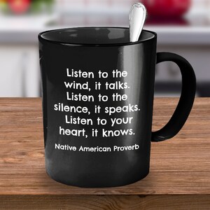 May include: Black ceramic mug with a silver spoon inside. The mug features white text that reads "Listen to the wind, it talks. Listen to the silence, it speaks. Listen to your heart, it knows. Native American Proverb."