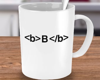 May include: White ceramic mug with a black graphic that says "<b>B</b>" in bold font.