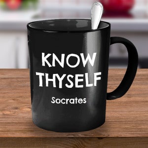 Può includere: Tazza da caffè in ceramica nera con testo bianco che recita "KNOW THYSELF Socrates".