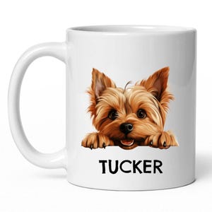 May include: White ceramic coffee mug with a brown and gold Yorkshire Terrier peeking over the rim. The dog's name, "TUCKER", is printed in black below the dog.
