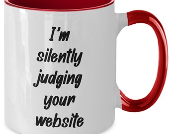 May include: White ceramic mug with a red interior and handle. The mug features the text "I'm silently judging your website" in black, bold font. A humorous gift for web designers or developers.