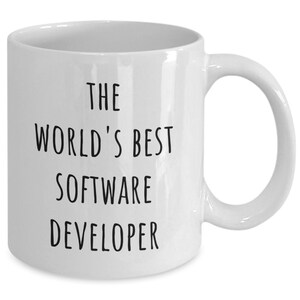 May include: White ceramic mug with a curved handle. The mug features the text "THE WORLD'S BEST SOFTWARE DEVELOPER" in black, centered on the front. A simple, everyday coffee mug.