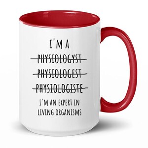 Può includere: Una tazza da caffè bianca con bordo e manico rossi. La tazza ha un testo nero che recita "Sono un fisiologo - Fisiologo - Fisiologo Sono un esperto in organismi viventi."