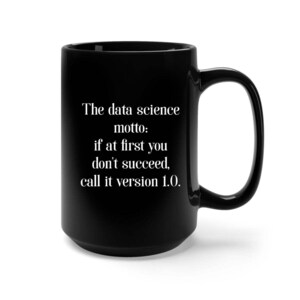 Puede incluir: Taza de café negra con texto blanco que dice "El lema de la ciencia de datos: si al principio no tienes éxito, llámala versión 1.0."