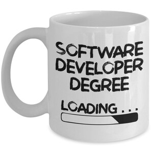 May include: White ceramic coffee mug with black text that reads "Software Developer Degree Loading..." with a progress bar underneath.