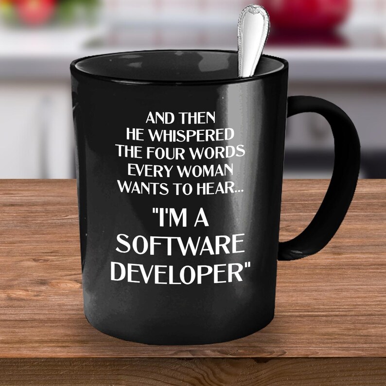May include: Black coffee mug with white text that reads "AND THEN HE WHISPERED THE FOUR WORDS EVERY WOMAN WANTS TO HEAR... "I'M A SOFTWARE DEVELOPER""