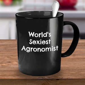May include: Black coffee mug with white text that reads "World's Sexiest Agronomist".