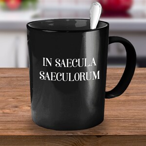 May include: Black coffee mug with white text that reads "IN SAECULA SAECULORUM".