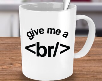 May include: White ceramic coffee mug with a black graphic that says "give me a <br/>" printed on the front.