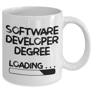 May include: White ceramic coffee mug with black text that reads "Software Developer Degree Loading..." with a progress bar underneath.