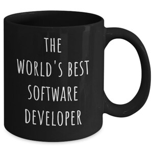 May include: A black ceramic mug with the text "THE WORLD'S BEST SOFTWARE DEVELOPER" in white. The mug has a curved handle and a glossy finish. A great gift for a software developer.