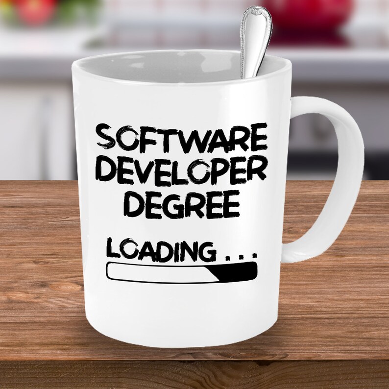May include: White ceramic coffee mug with black text that reads "Software Developer Degree Loading..." with a progress bar that is almost full.