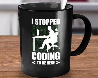 May include: Black coffee mug with white text that reads "I stopped coding <to be here>" and a silhouette of a person sitting at a computer. The background is a green matrix of 1s and 0s.