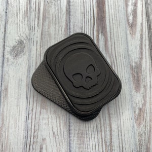 May include: Two black plastic skull-shaped keychains with a textured surface.