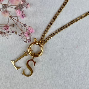 Puede incluir: Collar de cadena dorada con un dije con las letras "I" y "S".
