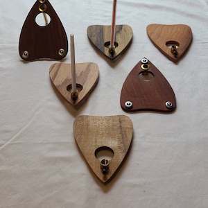 Może przedstawiać: Sześć drewnianych trójkątnych świeczników z otworem w środku. Świeczniki są wykonane z różnych rodzajów drewna i mają naturalne wykończenie.