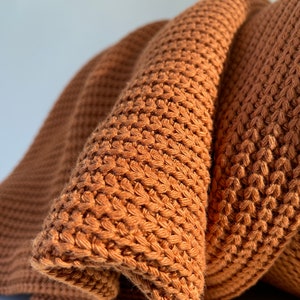 May include: A brown knitted throw blanket with a waffle stitch pattern.