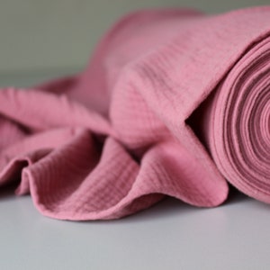 May include: A roll of pink waffle fabric. The fabric is soft and textured, and it is ideal for making clothes, blankets, or other crafts.
