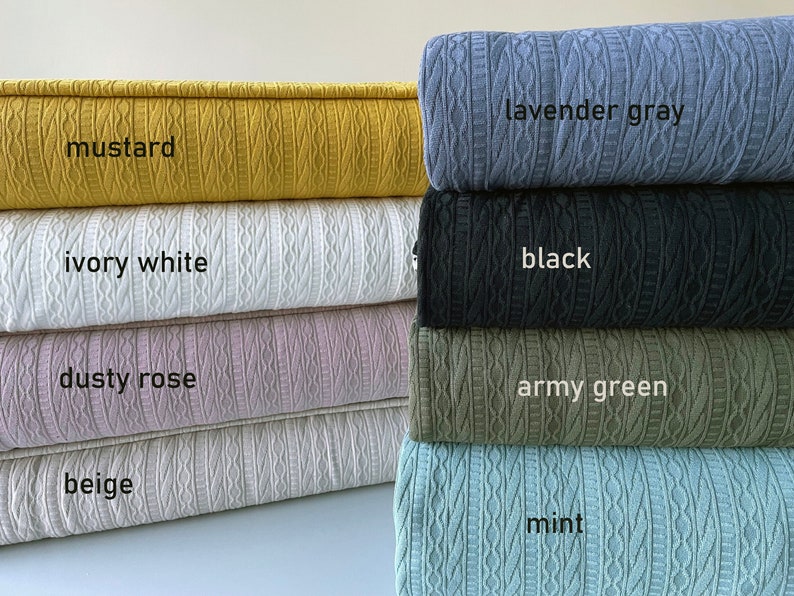 May include: A selection of cable-knit fabric samples in shades such as mustard, ivory white, dusty rose, beige, lavender grey, black, army green, and mint. Each sample is labelled with its colour.
