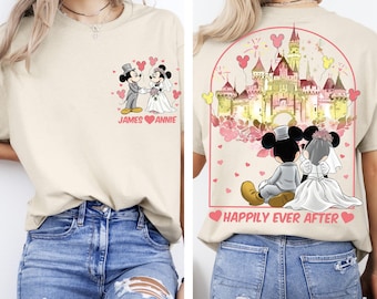 Puede incluir: Camiseta beige con una imagen de dibujos animados de Mickey y Minnie Mouse con ropa de boda. La parte delantera de la camiseta tiene los nombres "James" y "Annie". La parte trasera de la camiseta tiene un castillo y las palabras "Happily Ever After".