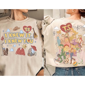 以下が含まれることがあります： カウボーイハット、ギター、赤いカーディガン、ブーツ、そして「TS I KNEW IT, I KNEW YOU」という文字が前面にプリントされたベージュのスウェットシャツ。背面には、様々なキャラクターのイラストのコラージュ、TSと書かれた赤いハート、音符が描かれています。