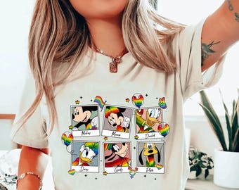 May include: A cream-colored t-shirt featuring six Disney character portraits with rainbow accents. The characters include Mickey, Minnie, Donald, Daisy, Goofy, and Pluto. The word "Natural" is printed in black at the top.