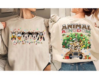 May include: Beige sweatshirt featuring Disney characters Pluto, Donald Duck, Mickey Mouse, Minnie Mouse, and Goofy wearing reindeer antlers and a string of Christmas lights. The back of the sweatshirt says "ANIMAL KINGDOM" with a jeep and more characters.