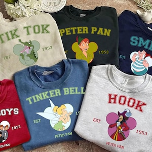 Puede incluir: Una colección de sudaderas de cuello redondo en varios colores, cada una con un personaje o tema diferente de Peter Pan. Los diseños incluyen "Tik Tok", "Peter Pan", "Smee", "Lost Boys", "Tinker Bell" y "Hook".
