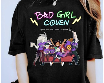 May include: Black t-shirt featuring a colorful graphic of characters from "The Owl House" animated series. The text "BAD GIRL COVEN" is displayed above the characters, with the phrase "BAD TOGETHER, STICK TOGETHER" below.