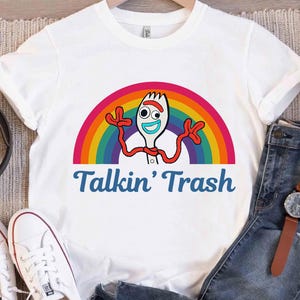 May include: White t-shirt with a rainbow and a cartoon character of a fork with a face and arms. The text "Talkin' Trash" is printed below the image.