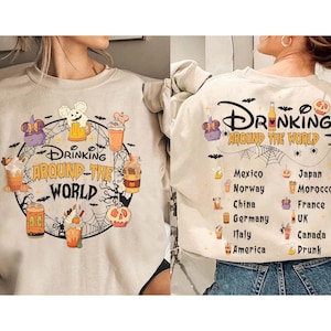 Op de afbeelding: Een beige sweatshirt met de tekst "Drinking Around The World". Het ontwerp bevat cartoon drankjes, vleermuizen en een spinnenweb. De achterkant toont landen met drank iconen.