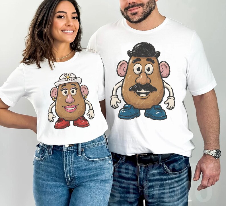 May include: Two white short-sleeved t-shirts. The left shirt features a graphic of a potato character wearing a white hat with a flower, gold hoop earrings, and red shoes. The right shirt features a potato character with a black bowler hat and blue shoes.